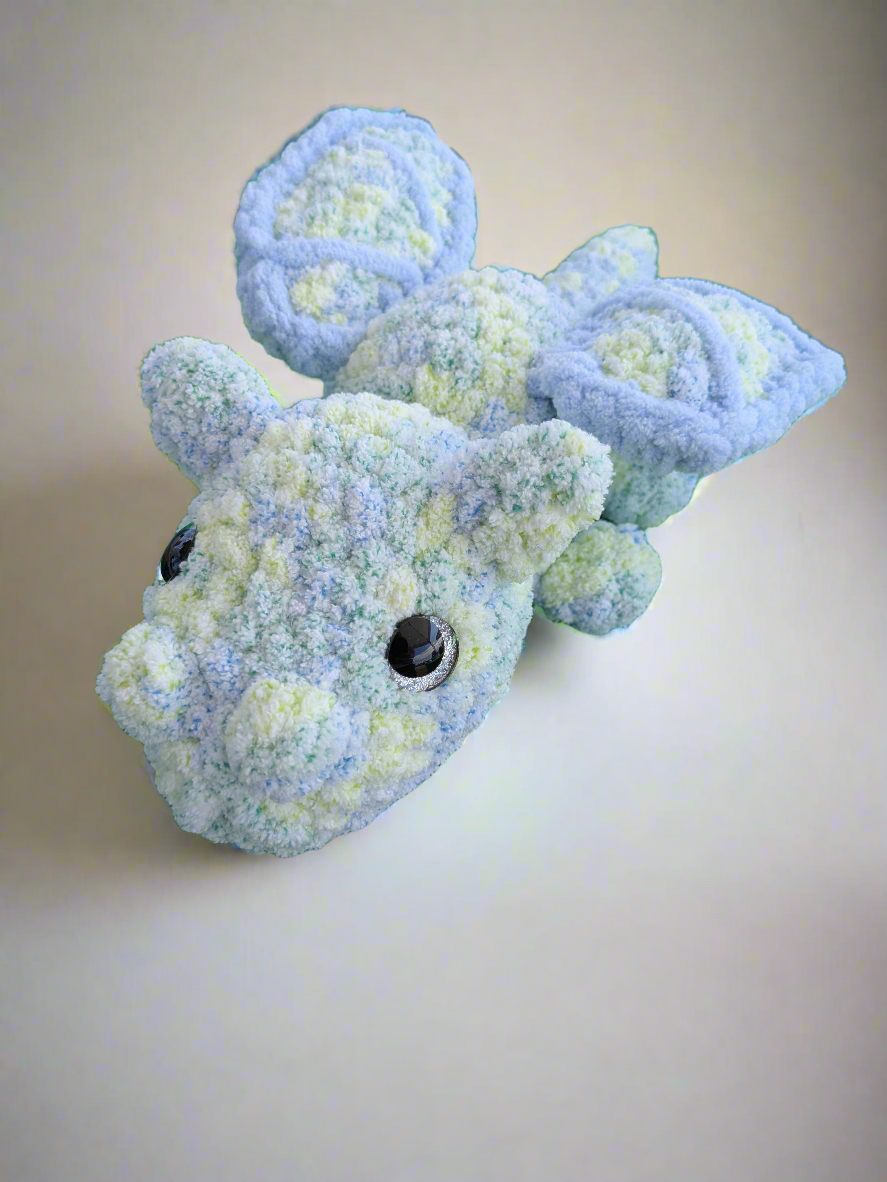 Blue and green textured dragon toy on a beige background