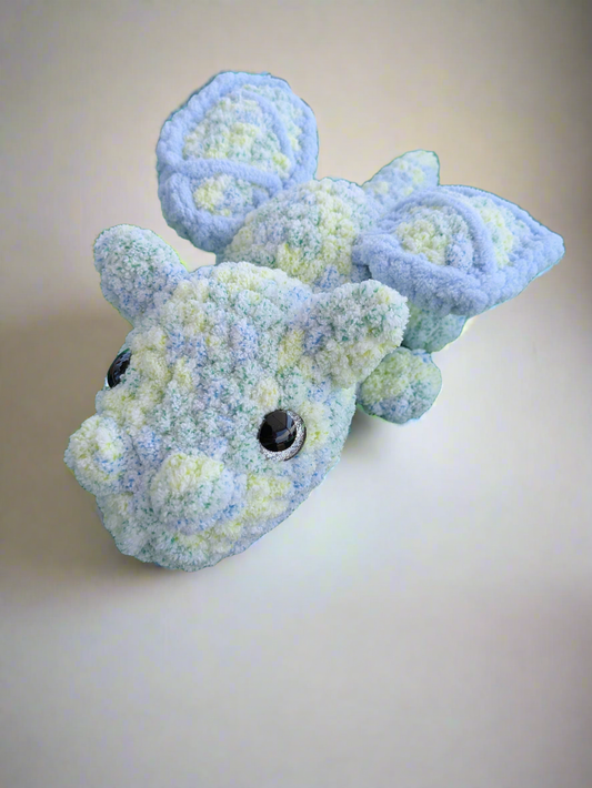 Blue and green textured dragon toy on a beige background